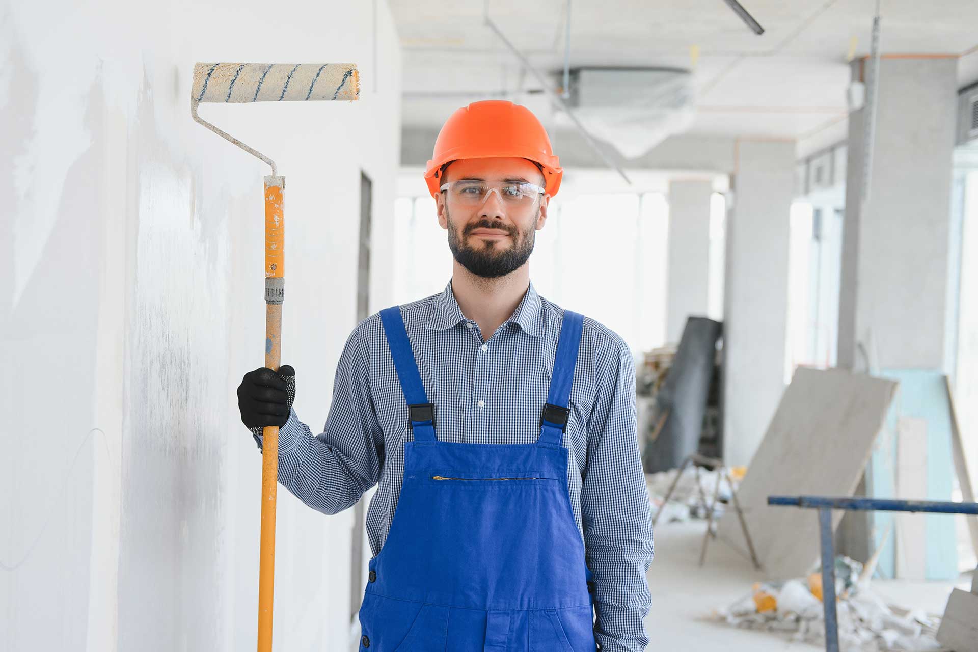 A construction worker holding a paint roller brush.